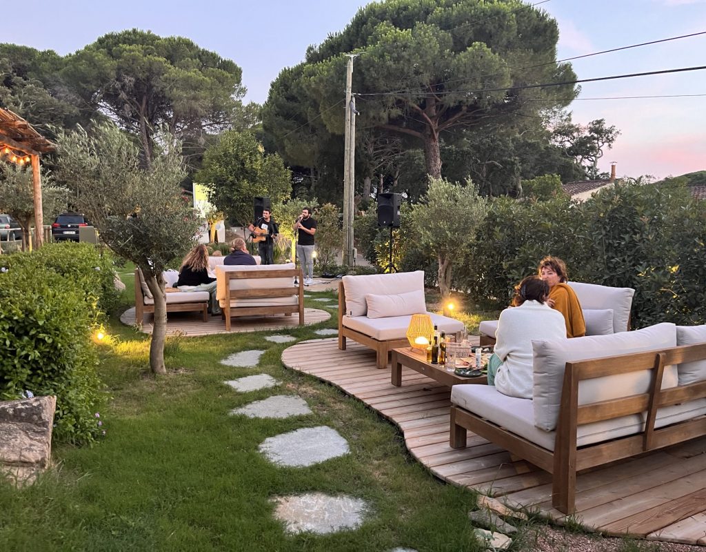 Coin cosy à côté de la terrasse du restaurant avec salons de jardin et chanteurs en live en arrière plan